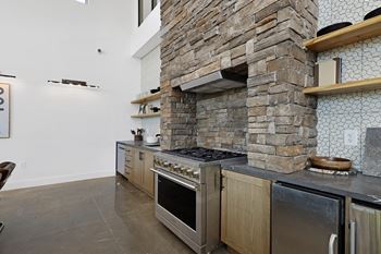 A modern kitchen with a stone wall and stainless steel appliances. at Terraces at High Mountain, Alabama, 35811